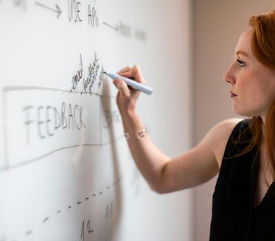 Une femme écrit sur un tableau blanc